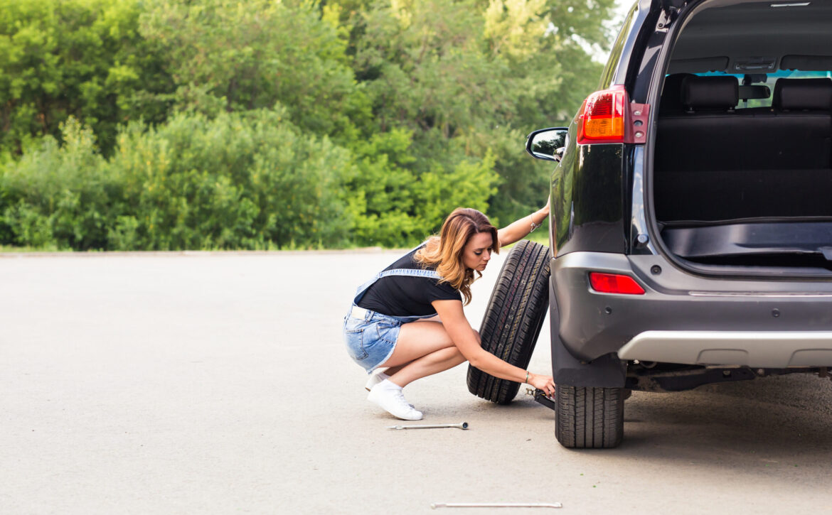 Woman changing tire on a road